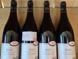 six bottles of red wine are lined up on a wooden shelf