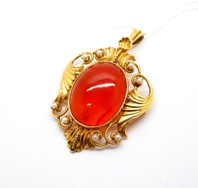 une image représentant un pendentif doré et rouge orné de perles, sur fond blanc