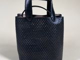 the small black bag is made from perfored leather and has a leather handle