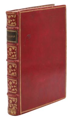 un vieux livre avec une couverture rouge et des bordures dorées sur fond blanc