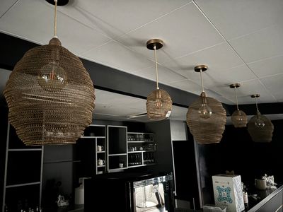 three wicker lamps hanging from the ceiling above a bar