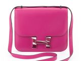 a close up of a pink purse with a strap on a white background