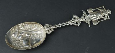 une vieille cuillère en argent contenant une pièce, posée sur une surface noire