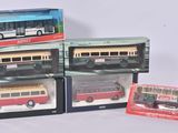 Trois maquettes de bus dans leur emballage sont posées les unes à côté des autres sur une table