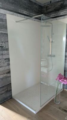 une douche avec une porte en verre dans une salle de bains