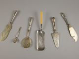 Plusieurs cuillères et couteaux en argent sont alignés sur une table
