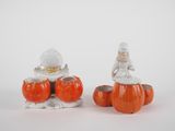 two ceramic figurines of people sitting on pumpkins