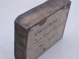 a small wooden box with writing on it on a white surface
