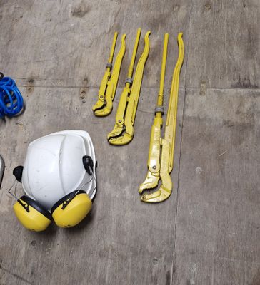 un casque de chantier, une paire de gants et deux clés posées par terre