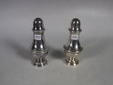 two silver salt and pepper shakers on a white surface