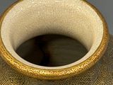 a vase that has a gold and white design on it