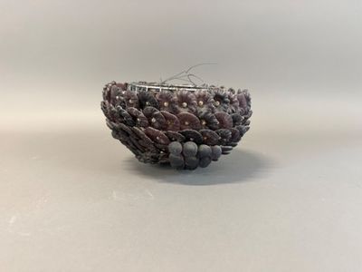 a close up of a beaded bowl on a white surface