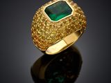 a close up of a gold ring with a green stone