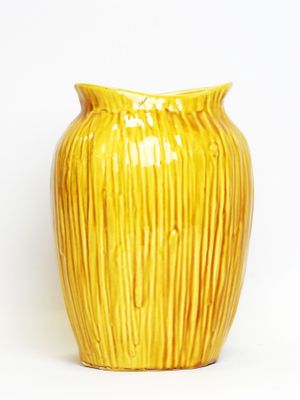a yellow vase that is sitting on a white surface