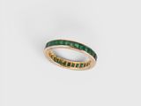 a close up of a gold ring with emerald stones