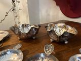 une table en bois sur laquelle sont posés des plats et des cuillères en argent