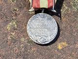 une médaille posée par terre, entourée d'un ruban