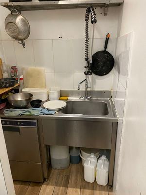 une petite cuisine équipée d'un évier et d'un micro-ondes fixé au mur