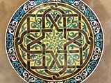 peinture représentant une assiette décorative ornée de motifs bleus et jaunes sur fond marron