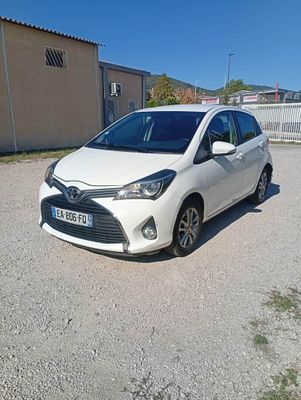 La petite voiture blanche est garée sur le parking, à côté d'un immeuble.