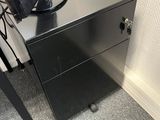a desk with a lamp on top of it next to a chair