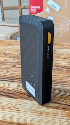 une photo d'une batterie externe noire posée sur une table en bois