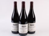 trois bouteilles de vin rouge sont alignées sur une surface blanche