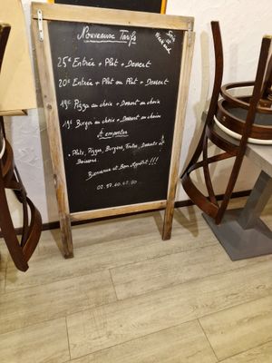 un tableau noir sur lequel est inscrit un menu, à côté de deux chaises