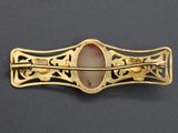 an image of a gold broochle with a pink stone in the center