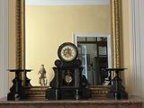 une cheminée surmontée d'une horloge, devant un miroir