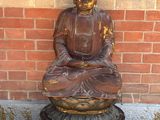 statue d'un Bouddha assis sur un socle devant un mur de briques