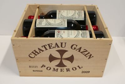 des bouteilles de vin dans une caisse en bois posée sur une table blanche