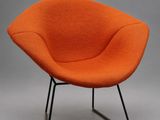 une chaise orange avec des pieds noirs et un piètement noir