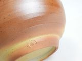 a close up of a brown vase on a white surface