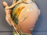 un vase orné d'une femme, posé sur une table