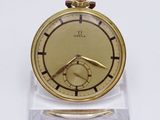une montre de poche en or posée sur un socle transparent, sur une surface blanche