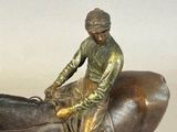 bronze statue of a man riding a horse with a saddle