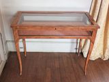 une petite table en bois avec un plateau en verre, posée sur un parquet en bois massif