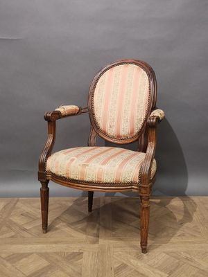 a wooden chair with a striped upholstered back and arms