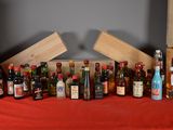 many bottles of alcohol sitting on a table with a red table cloth