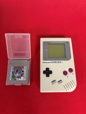 an old gameboy with a game and a case on a red table