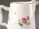 a white pitcher with pink flowers on it on a table