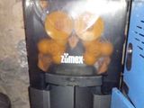 a machine that has oranges in it and is next to a stack of plates