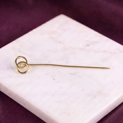 un gros plan d'une broche en or posée sur une surface en marbre