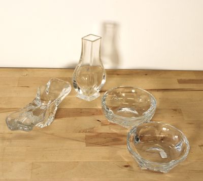 trois bols en verre et un vase en verre posés sur une table en bois