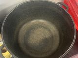 a black pan sitting on top of a counter next to a red container