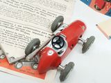 a red toy car sitting on top of an open book
