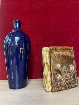 two vases sitting on a shelf next to a red wall