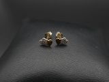 une paire de boucles d'oreilles en or posées sur une surface en cuir noir