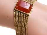 a close up of a woman ' s arm wearing a bracelet with a red stone